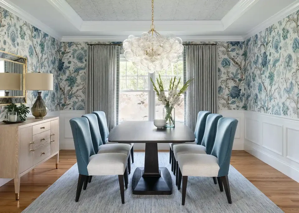 Blue botanical wallpaper around a dining table in a bright room