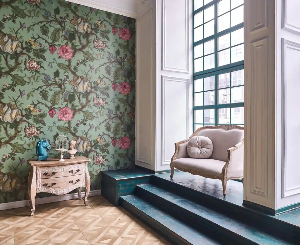 Floral wallpaper and a sculptural chair beside a tall window